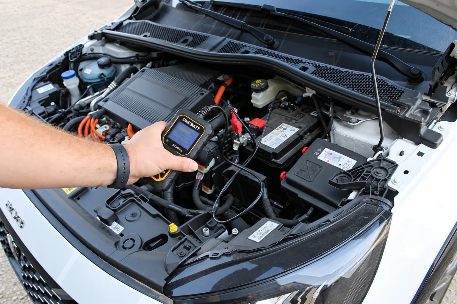 Testeur ONE BATT branché sur la batterie d'un véhicule, capot ouvert